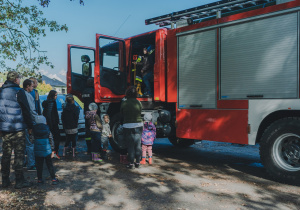 Dzieci czekają na wejście do samochodu strażackiego